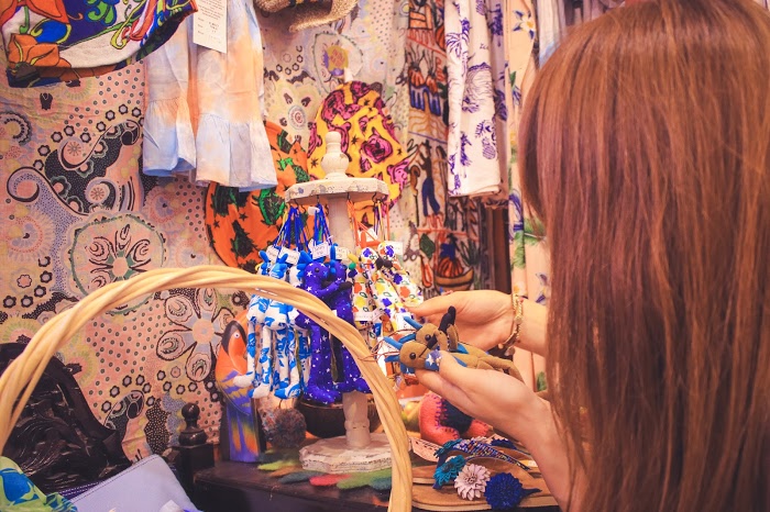 フリー写真画像『宮古島のかわいい雑貨屋さん『がじゅまる』で人形を手に取る女の子』[ID:9036]