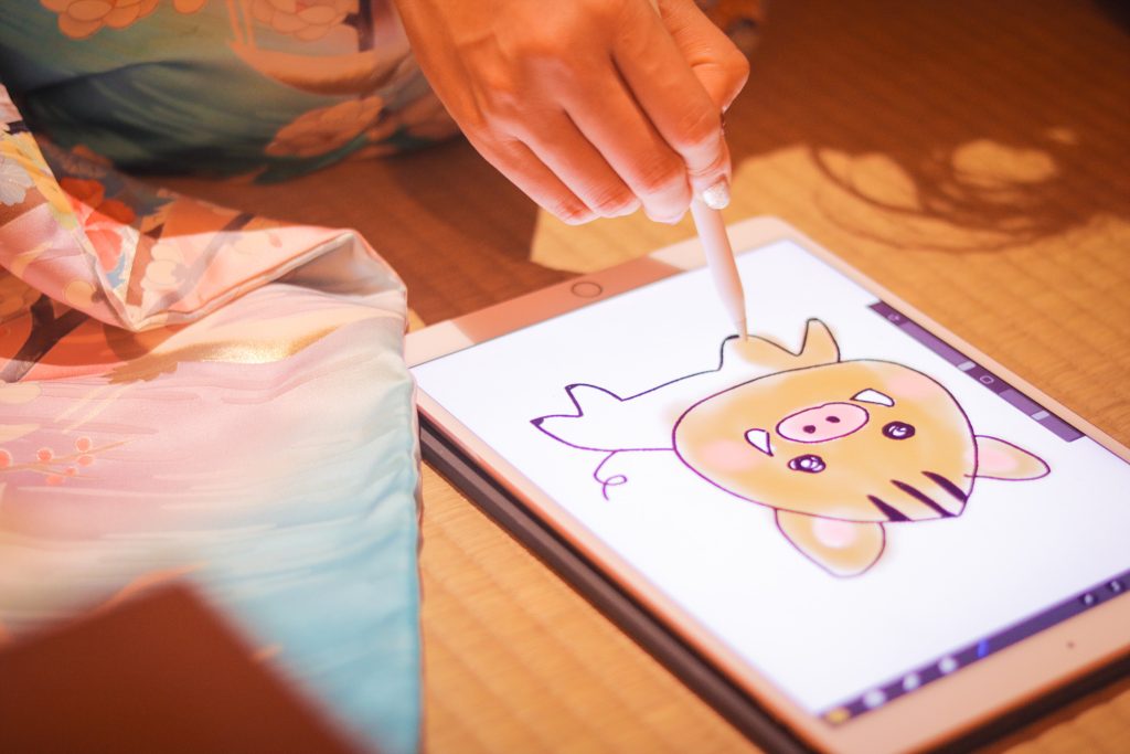 フリー写真画像『iPad ProとApple Pencilを使って年賀状のイラストを描くイマドキな女の子』[ID:9481]