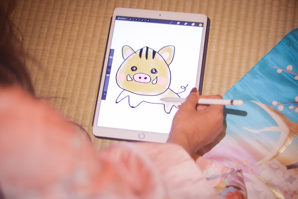 フリー写真画像『iPad Proのお絵かきソフトで年賀状用のイラストに色を塗る女の子』[ID:9485]