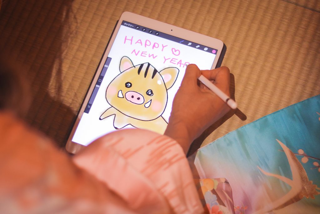 フリー写真画像『iPad Proで描いたイラストに『HAPPY NEW YEAR』の文字を書き入れる様子』[ID:9490]