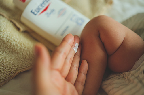 フリー写真画像『ムチムチの赤ちゃんの足に保湿剤を塗る手』[ID:12272]