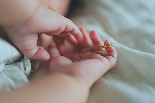 フリー写真画像『赤ちゃんの小指にはまっているポリゴン型のベビーリング』[ID:12286]
